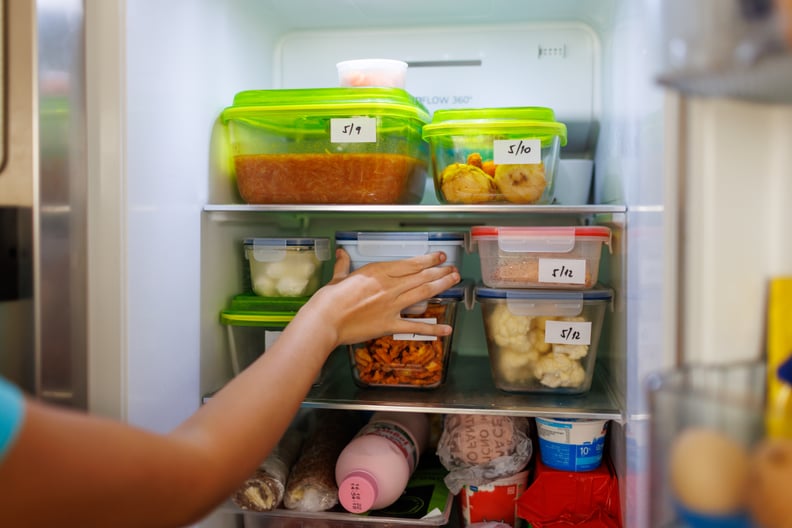 Cold food leftovers packaged in boxes inside a home fridge with dates written on.